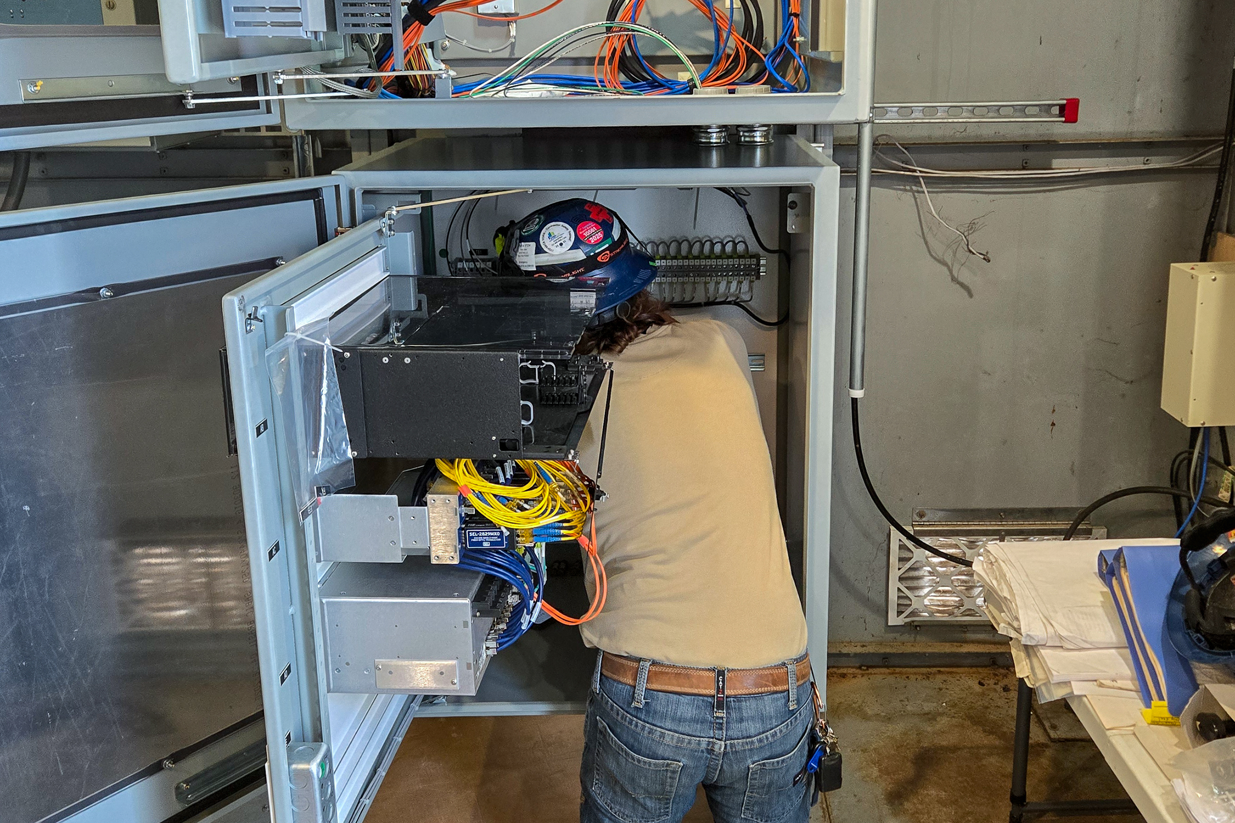 Electrical technician installing cabling into an electrical cabinet.